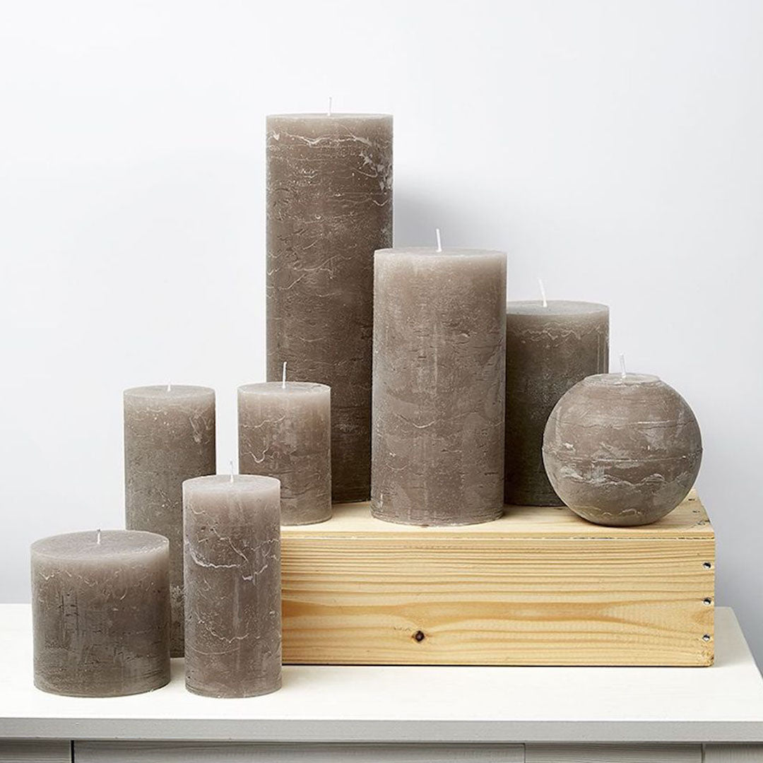 Velas cilíndricas color Stone en varios tamaños, ideales para decoración de interiores y eventos.